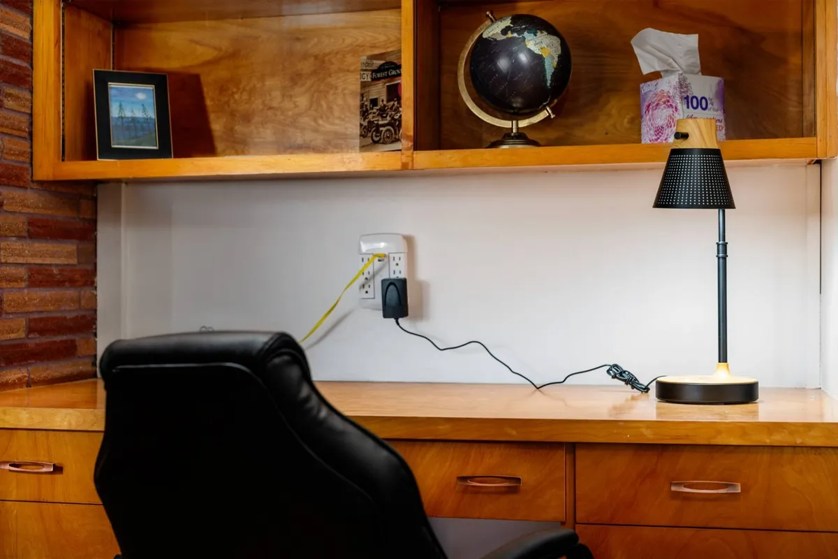 A focused and serene workspace featuring a desk lamp, globe, framed picture, and tissue box. The setting feels studious and inspiring, suggesting moments spent planning trips or reflecting on adventures.