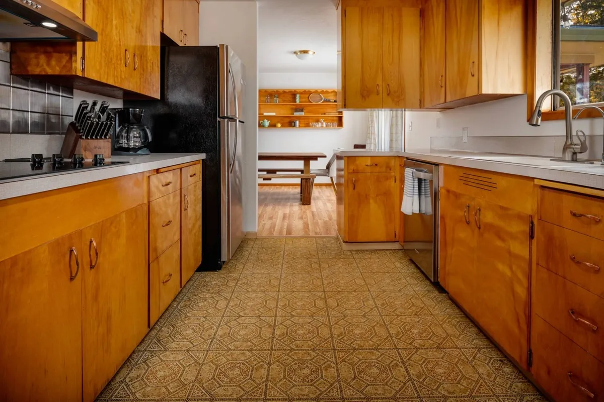 A modern, functional kitchen highlighted by wooden cabinetry, stainless steel appliances, a central island, and decorative shelves. The space is designed for cooking, entertaining, and spending quality time together as meals are prepared and shared.